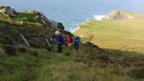 Guests hiking scenic coastal path with ocean views. Experience outdoor adventure near the seaside, perfect for nature lovers.