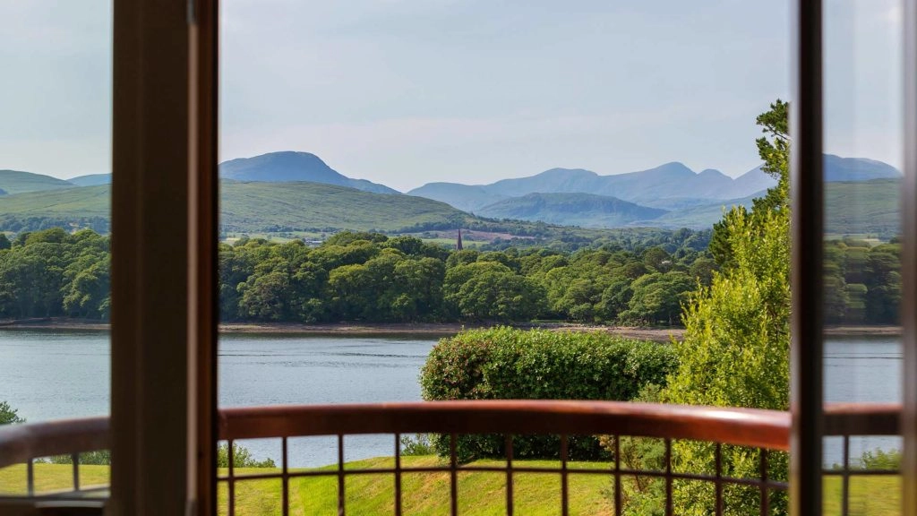 Stunning mountain and lake view from hotel room window, featuring lush greenery and serene landscape.