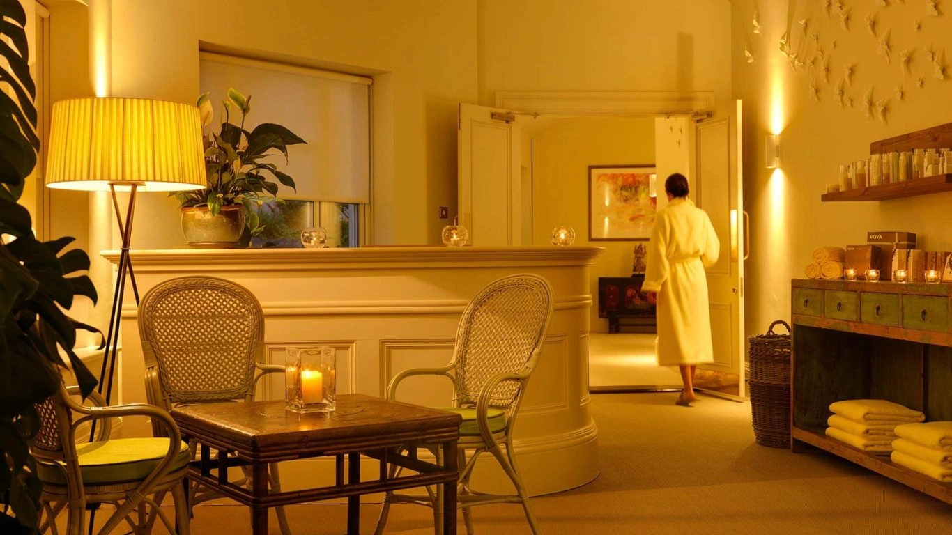 Serenity in warm-lit hotel spa with cosy seating, candles, and lush plants, inviting relaxation and rejuvenation.