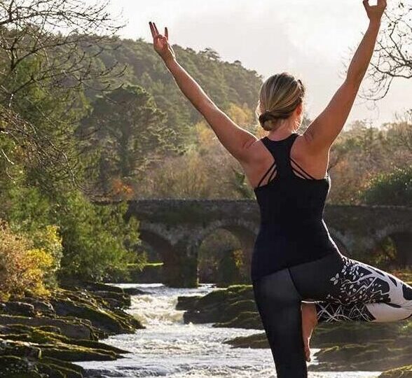 Woman doing yoga outside by the waterfalls at Sheen Falls Lodge