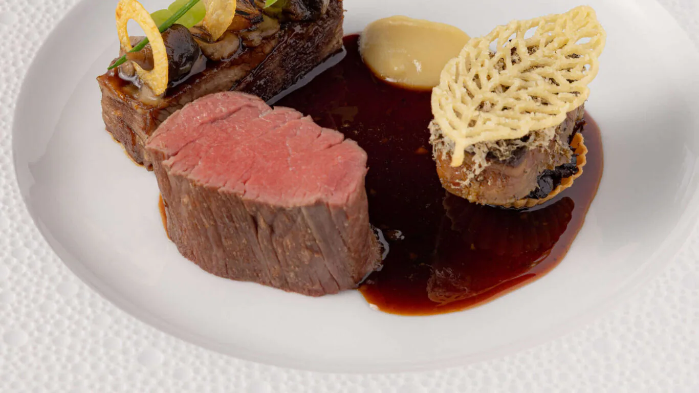 Exquisite gourmet dish with tender beef, rich jus, and elegant garnish at luxury hotel restaurant.