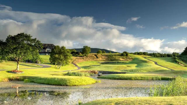 Luxurious golf course with scenic views, lush greens, inviting clubhouse, and serene pond under a bright blue sky.