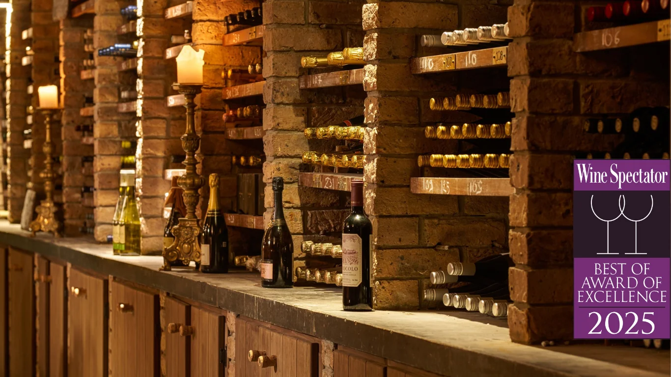 Wine bottles are stored in brick shelves with various labels visible; candles and decorative items sit on the counter. A 