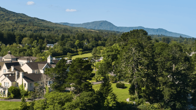 A scenic view of houses and lush greenery by a river under a clear blue sky, with