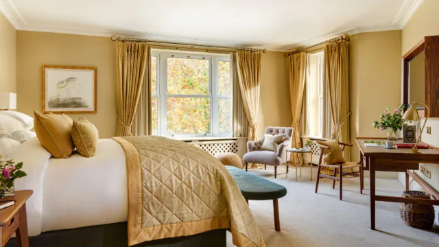 Luxurious hotel room with plush bed, elegant armchair, scenic window view, and warm tones for a relaxing stay.