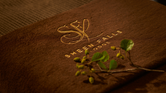 Luxurious brown fabric with Sheen Falls Lodge logo and green leaves, symbolising nature and relaxation.