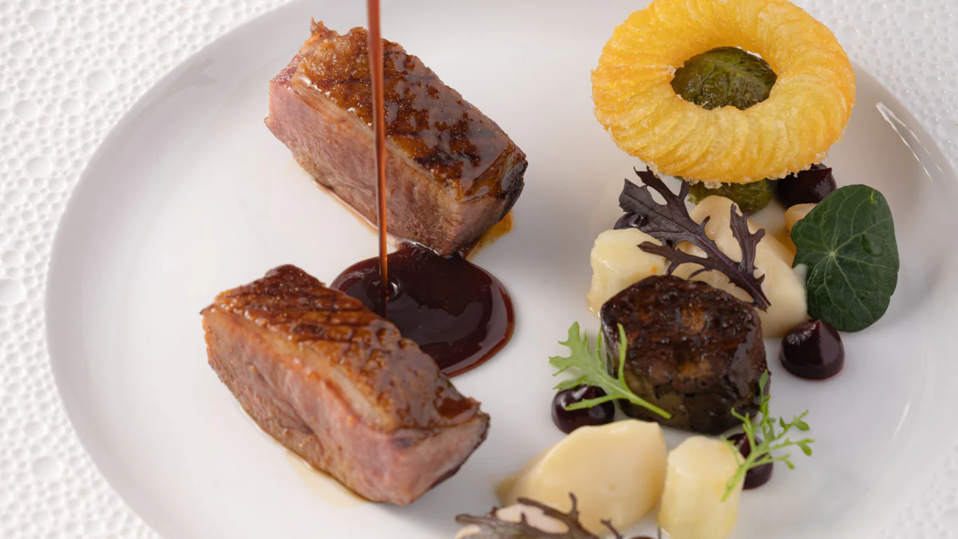 Elegant gourmet dish with tender meat, rich sauce, topped with onion ring, curated greens and delicate mashed potato.