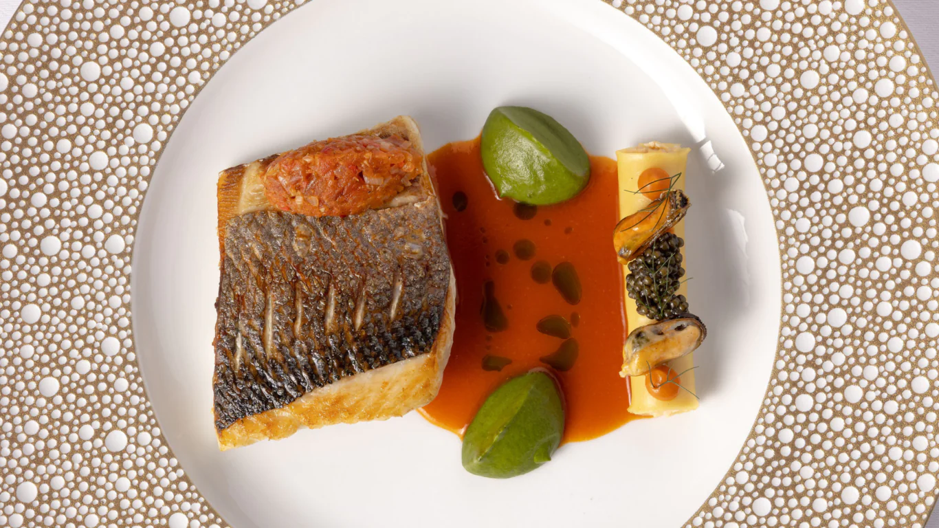 Elegant gourmet fish dish with green garnish and seafood on artistic plate, capturing a luxurious dining experience.