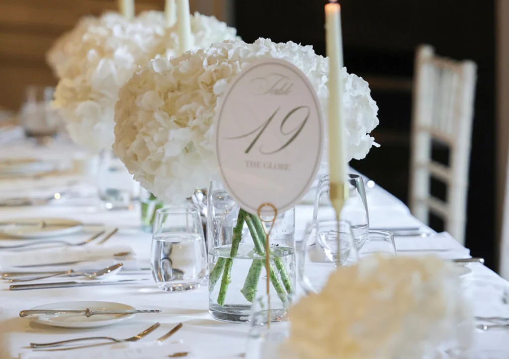 Elegant dining setup with white floral centrepieces, fine silverware, and soft candlelight at a luxury hotel event.