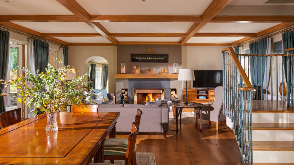 Luxurious hotel suite with cosy fireplace, elegant dining area, and stylish wooden staircase, perfect for a relaxing stay.