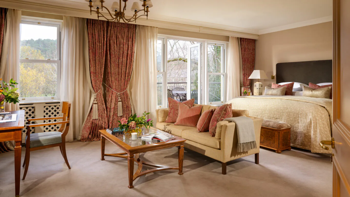 Elegant hotel room with plush sofa, large bed, and garden view, offering a cosy retreat with luxurious decor.
