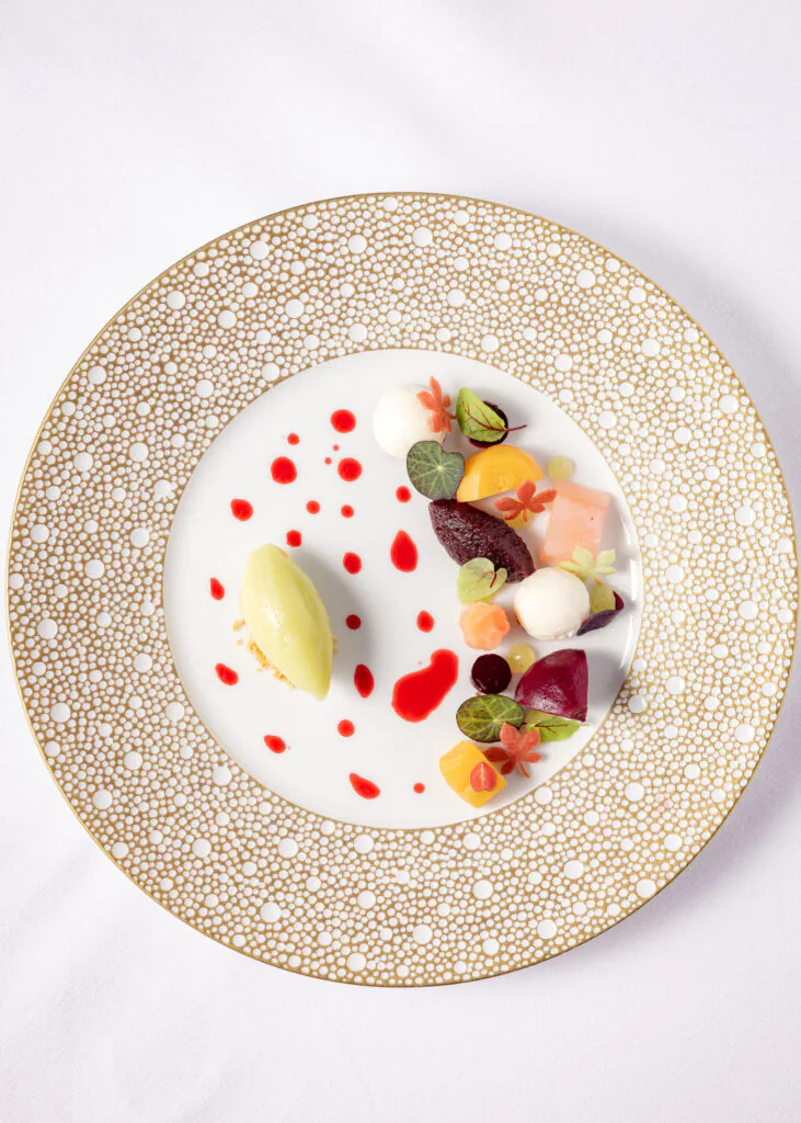 Gourmet dessert on elegant plate with colourful garnishes and sauce, showcasing luxury dining experience at hotel restaurant.