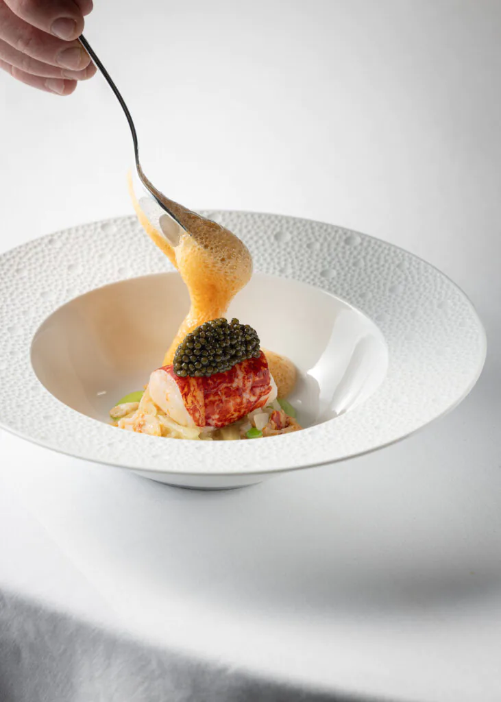 Luxurious lobster dish with caviar and foam, served on elegant tableware at the hotel's fine dining restaurant.